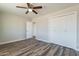 Bedroom featuring a closet, an open door, a ceiling fan, and wood-look flooring at 11214 N 105Th Ave, Sun City, AZ 85351