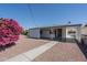 Charming house exterior with a covered patio and a beautiful bougainvillea tree in a gravel yard at 11214 N 105Th Ave, Sun City, AZ 85351