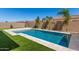 Inviting backyard pool surrounded by travertine decking and artificial turf at 11807 W Parkway Ln, Avondale, AZ 85323