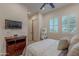 Bright bedroom featuring plantation shutters, TV, dark wood dresser and ceiling fan at 1275 E Verde Blvd, Queen Creek, AZ 85140