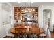 Elegant dining room featuring a modern chandelier and a built-in dry bar with glass shelving and ample storage at 1275 E Verde Blvd, Queen Creek, AZ 85140
