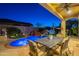 Inviting backyard with a blue-lit pool, a waterfall feature, and a covered patio with dining set at 1275 E Verde Blvd, Queen Creek, AZ 85140