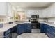 Stylish kitchen featuring stainless steel appliances, navy cabinets, light countertops, and tile flooring at 13026 W Peach Blossom Dr, Sun City West, AZ 85375