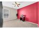 Bright bedroom featuring neutral carpet, a ceiling fan, and a red accent wall at 1316 E Spencer St, Casa Grande, AZ 85122