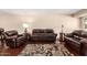 Cozy living room with hardwood floors, area rug, and comfortable brown leather seating at 13621 N Emberwood Dr, Sun City, AZ 85351