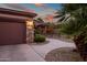 Charming single-story home at sunset with a stone facade, desert landscaping and a welcoming walkway at 15131 W Daybreak Dr, Surprise, AZ 85374