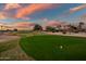 Scenic view of well-maintained golf course at sunset with colorful sky and mature palm trees at 15131 W Daybreak Dr, Surprise, AZ 85374