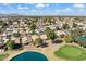 Picturesque aerial view of homes in a neighborhood, showcasing a serene pond and a green golf course with blue skies at 17077 N Zuni Trl, Surprise, AZ 85374