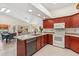 Well-lit kitchen with modern appliances, wood cabinets, tile flooring, an island and an open view to the living area at 17077 N Zuni Trl, Surprise, AZ 85374