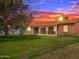 Charming brick home with covered porch, lush lawn, and beautiful sunset backdrop at 1736 E Coronado Rd, Phoenix, AZ 85006