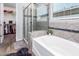 Modern bathroom features a glass shower, soaking tub, and a view into a closet at 17496 W Summit Dr, Goodyear, AZ 85338