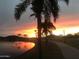 Peaceful pond view with palm trees, a walking path, and a stunning sunset sky at 17496 W Summit Dr, Goodyear, AZ 85338