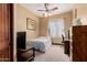 This cozy bedroom features a ceiling fan and a dark wood desk at 18332 W Latham St, Goodyear, AZ 85338