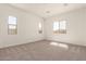 A large empty bedroom with three windows, neutral carpet, and white walls providing lots of natural light at 25372 N 158Th Ct, Surprise, AZ 85387