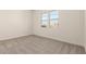 A bright, carpeted bedroom with white walls and a large window showing the neighborhood outside at 25372 N 158Th Ct, Surprise, AZ 85387