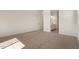 An empty bedroom featuring neutral carpet, white walls, and a peek into the ensuite bathroom at 25372 N 158Th Ct, Surprise, AZ 85387
