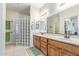 Well-lit bathroom with double sink vanity, tiled floor, and walk-in glass block shower at 2662 S Springwood Blvd # 461, Mesa, AZ 85209