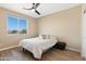 This bedroom features a ceiling fan, wood floors, neutral walls, a large sunny window, and a cozy bed at 34515 N 142Nd St, Scottsdale, AZ 85262