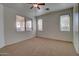 Bright bedroom featuring plush carpet, a ceiling fan, and multiple windows for ample natural light at 40716 N Hudson Trl, Anthem, AZ 85086