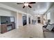 Open-concept living area flowing into kitchen, features tile flooring, ceiling fan, and cozy sofa at 40716 N Hudson Trl, Anthem, AZ 85086