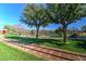 Scenic park view featuring a mini-train track, lush grass, shady trees, and a distant pond at 40716 N Hudson Trl, Anthem, AZ 85086