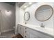 Bathroom featuring a double sink vanity, modern lighting, a walk-in shower and round mirrors at 4202 E Broadway Rd # 211, Mesa, AZ 85206