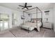 A bright main bedroom featuring a four-poster bed, neutral tones, and a glimpse into the ensuite bathroom at 4226 E Marlene Dr, Gilbert, AZ 85296