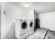 Laundry room equipped with a front-load washer and dryer set on risers, along with a utility sink and water heater at 5226 W Freeway Ln, Glendale, AZ 85302