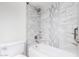 Close-up of a renovated shower featuring stylish gray tiles with a decorative vertical accent stripe and a built-in shower caddy at 5226 W Freeway Ln, Glendale, AZ 85302