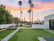 Stunning backyard with a putting green, pool, and mature palm trees against a beautiful sunset sky at 6601 E Hearn Rd, Scottsdale, AZ 85254