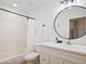 Well-lit white bathroom with a modern round mirror, bright vanity, bathtub, and shower featuring a shower curtain at 6601 E Hearn Rd, Scottsdale, AZ 85254