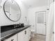 Bright bathroom with a black granite countertop, white vanity, and a round mirror with modern fixtures at 6601 E Hearn Rd, Scottsdale, AZ 85254