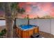 Hot tub with wood panels and steps, in front of a fence and palm trees at 6601 E Hearn Rd, Scottsdale, AZ 85254