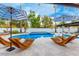 Pool area featuring modern lounge chairs, umbrellas, and a clear view of the pool and surrounding landscape at 6601 E Hearn Rd, Scottsdale, AZ 85254