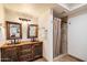 A bathroom featuring a rustic wood vanity with dual sinks, framed mirrors, and a shower with earth-toned stone tiles at 8165 E Del Marino Dr, Scottsdale, AZ 85258