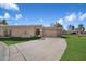 Beige single-story home with a well-maintained lawn, desert plants, a curved driveway, and a two-car garage at 8165 E Del Marino Dr, Scottsdale, AZ 85258