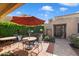 Private patio with an orange umbrella and an outdoor seating area surrounded by lush, manicured hedges at 8165 E Del Marino Dr, Scottsdale, AZ 85258