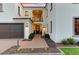 Elegant home entrance featuring a small balcony, dark wood doors with brick-paved walkway, desert foliage, and green lawn at 9467 E Rockwood Dr, Scottsdale, AZ 85255