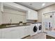 Bright laundry room featuring white cabinets, gray countertops, stainless steel hardware, and modern appliances at 9467 E Rockwood Dr, Scottsdale, AZ 85255