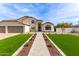 Charming two-story home featuring a three-car garage, manicured lawn, and beautiful desert landscaping at 951 N Poinciana Rd, Gilbert, AZ 85234