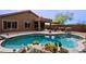 Stunning pool area featuring a covered patio with outdoor furniture, desert landscaping, rock accents, and lush flowering plants at 10250 E Morning Star Dr, Scottsdale, AZ 85255