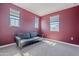 An unfurnished bedroom with three windows and a dark gray couch against a red wall at 1255 N Arizona Ave # 1246, Chandler, AZ 85225