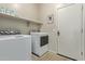 Bright laundry room with modern washer and dryer units, plus storage shelf at 13225 W Rowel Rd, Peoria, AZ 85383