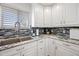 Close up of updated kitchen features white cabinets, stylish backsplash, and stainless steel sink at 19700 N 76Th St # 2044, Scottsdale, AZ 85255