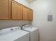 Convenient laundry room featuring a washer, dryer, and overhead wood cabinets at 2367 W Dusty Wren Dr, Phoenix, AZ 85085
