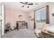 Charming Bedroom featuring a crib, rocking chair, pink accent wall, and natural light at 24032 N Rooster Rd, Florence, AZ 85132