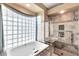 Luxurious bathroom featuring a soaking tub, a glass-enclosed shower, and a unique glass-block window at 25043 S Hollygreen Dr, Sun Lakes, AZ 85248