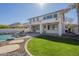 A spacious backyard oasis featuring a rock waterfall pool, lush lawn, and covered patio at 2506 E Bridgeport Pkwy, Gilbert, AZ 85295