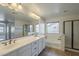 Bathroom featuring a double sink vanity, large mirror, soaking tub, and a glass-enclosed shower at 2506 E Bridgeport Pkwy, Gilbert, AZ 85295