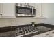 Close-up of the kitchen with granite counters, a stainless steel microwave, and gas cooktop at 2506 E Bridgeport Pkwy, Gilbert, AZ 85295